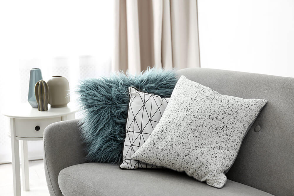 Fun, colorful decorative pillows on grey couch in downtown loft apartment