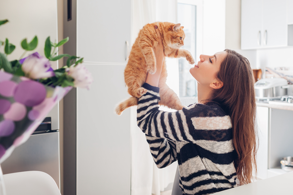 A young woman picking up her orange cat