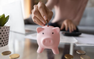 A young woman putting coins into a piggy bank
