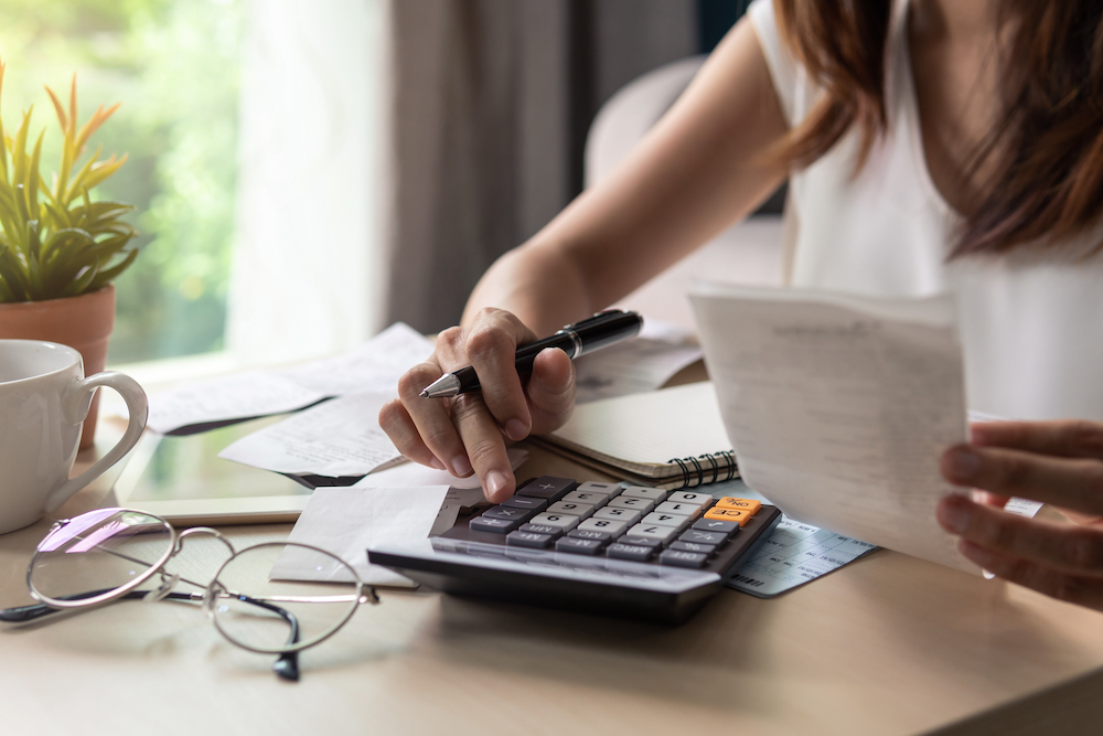 A woman sits and calculates her rent budget