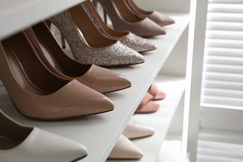 Several pairs of high heeled shoes on a rack in a closet