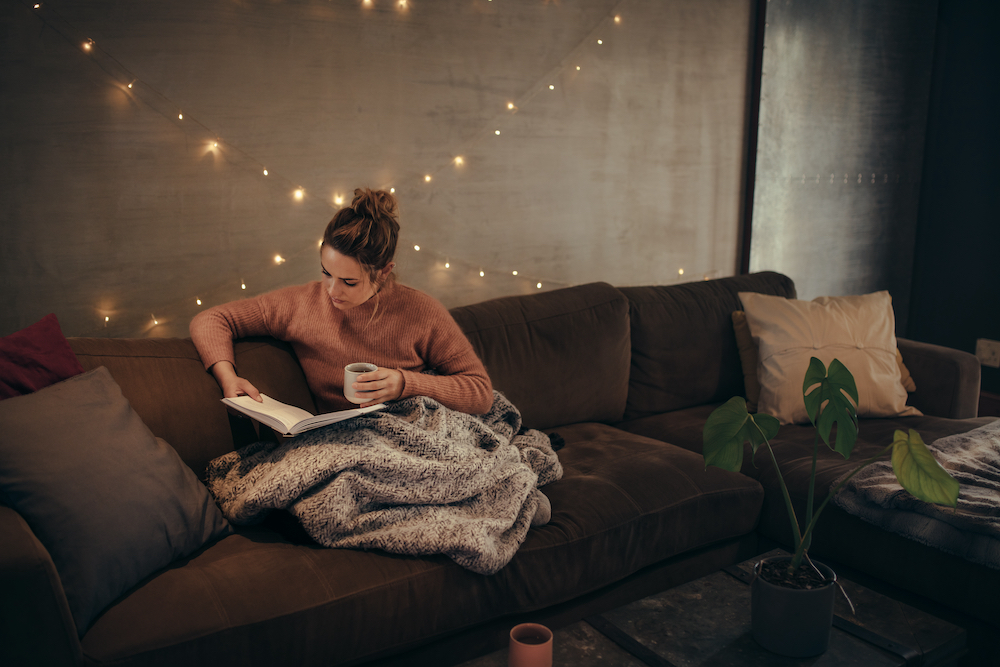A young woman reading a book in her cozy loft apartment