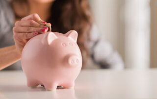 A woman puts coins into a piggy bank to save for an apartment