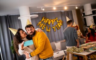 A fun, happy couple takes a selfie with their phone at a NYE party