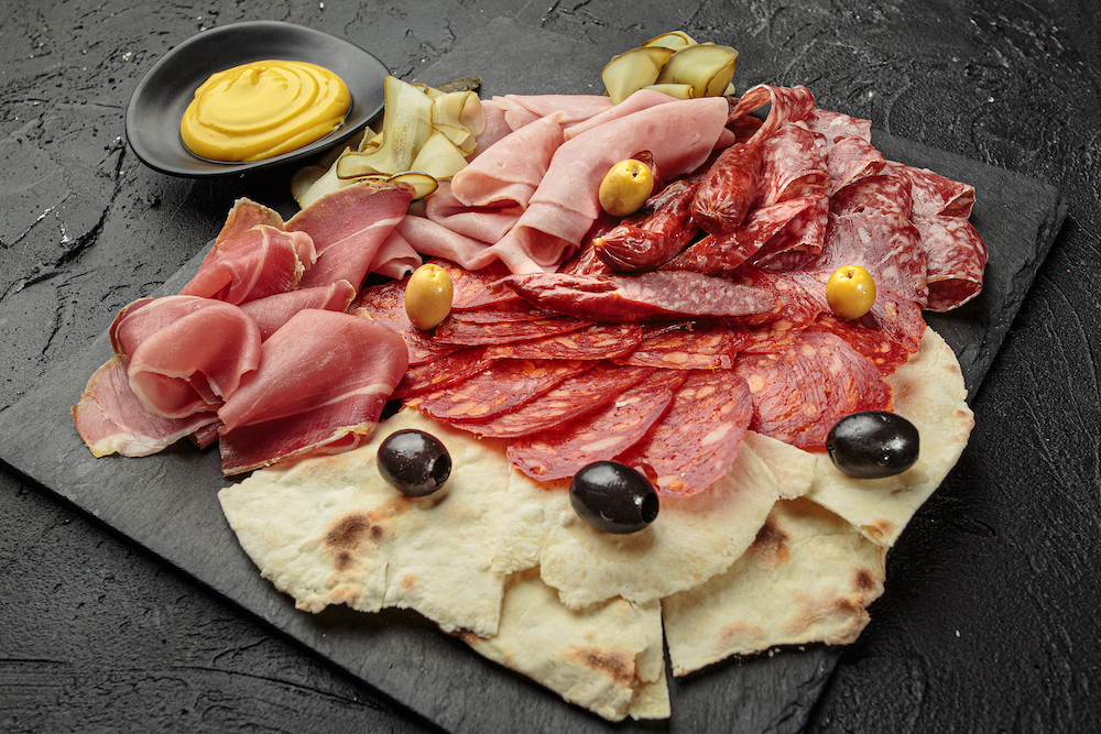 A charcuterie board with meat and olives spread out on a table