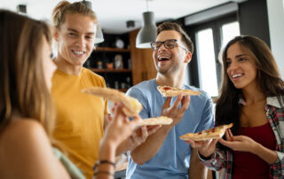 A group of friends enjoying pizza at a party at the Saint Joe apartments