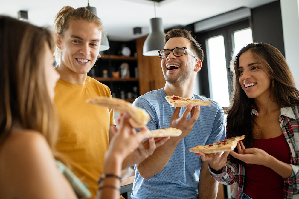 A group of friends enjoying pizza at a party at the Saint Joe apartments