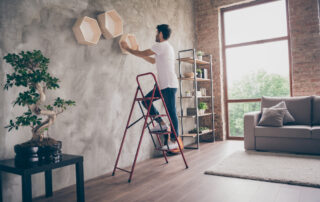 A man hanging up decor in his new loft apartment